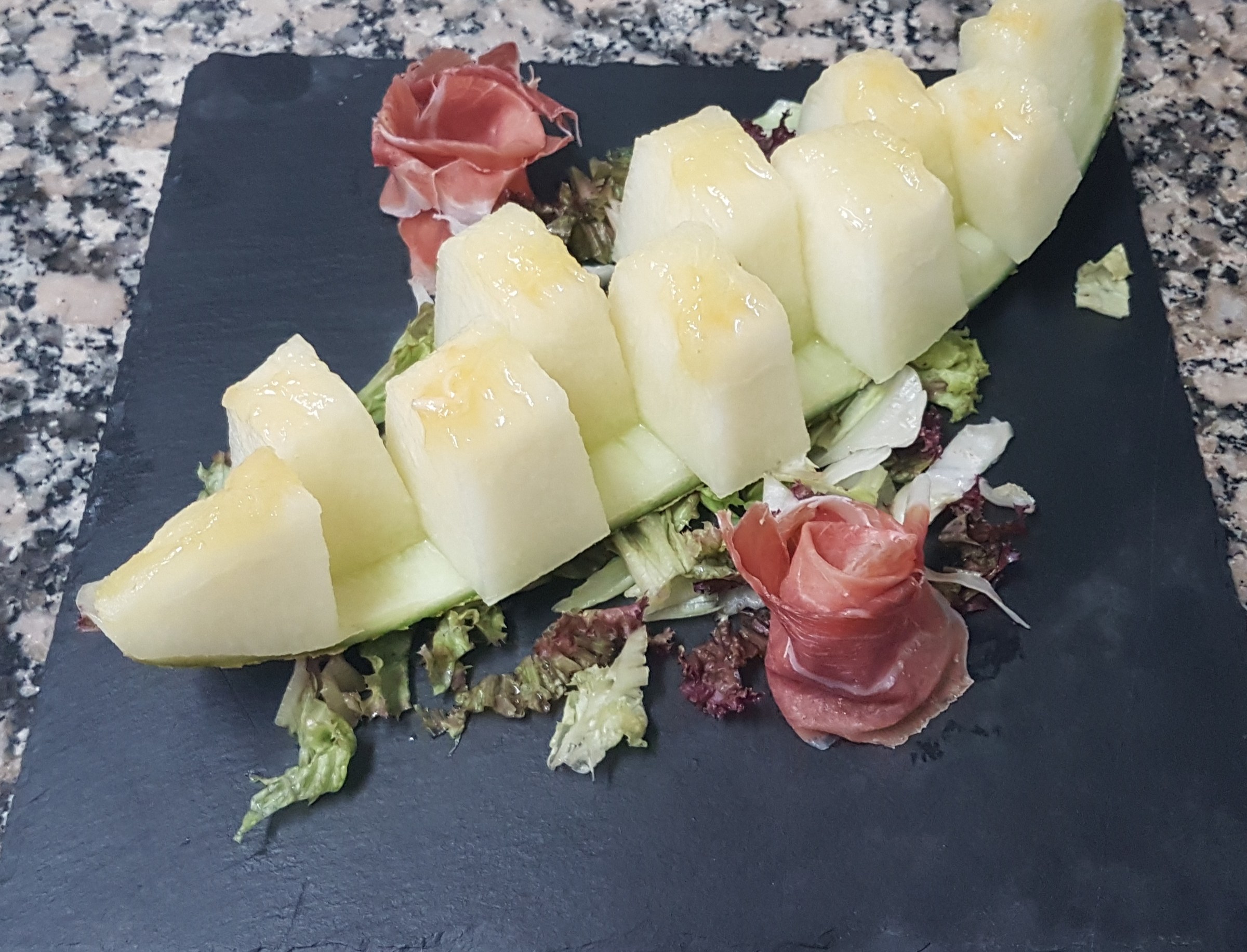 Melón con jamón presentado sobre pizarra